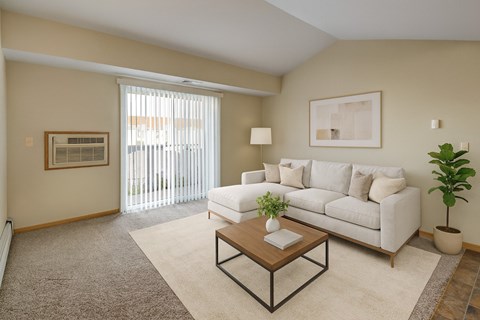 A living room with a white couch, a coffee table, and a plant.