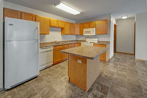 A kitchen with a white refrigerator, wooden cabinets, and a granite countertop.