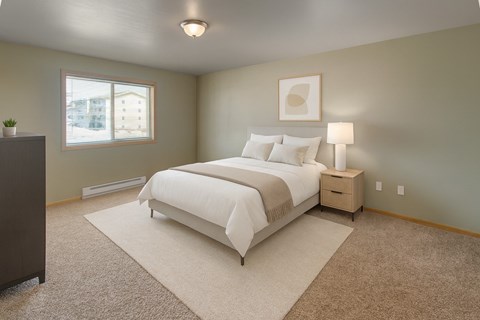 A bedroom with a large bed and a nightstand with a lamp.