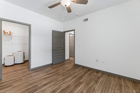 A room with a ceiling fan and wooden flooring.