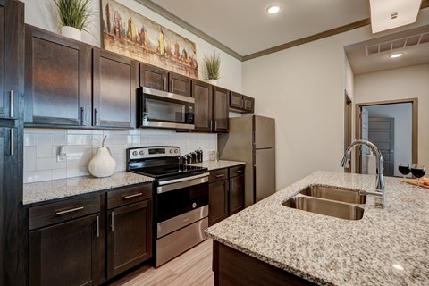 A kitchen with dark brown cabinets and a granite countertop.