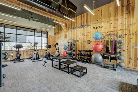 A gym with a variety of equipment and a wall with inspirational quotes.