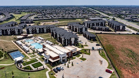 A large building complex with a swimming pool in the foreground and rows of houses in the background.