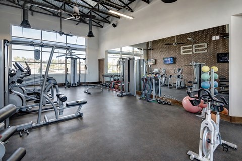 A gym with a variety of exercise equipment including treadmills, weights, and exercise balls.