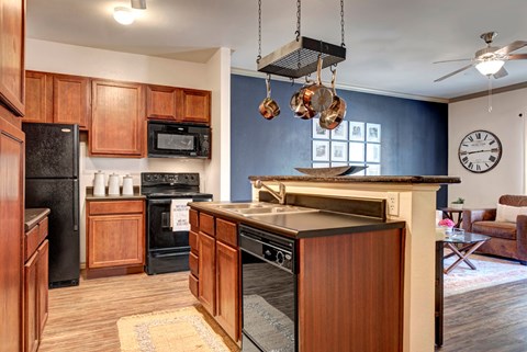 A kitchen with wooden cabinets and a black refrigerator.