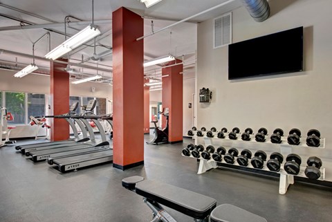 A spacious fitness center here at Aviare Arts District with treadmills, free weights, weight benches, and mounted TVs, creating a bright and functional environment for strength training and cardio workouts.