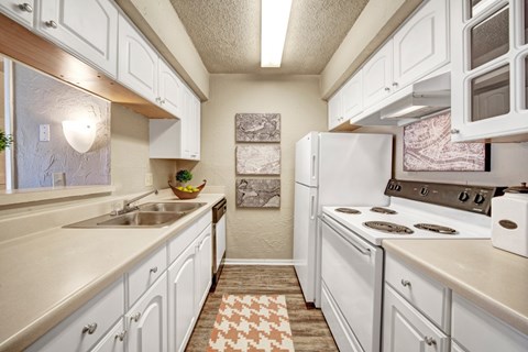 A kitchen with white cabinets and a checkered rug on the floor.