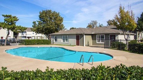 A swimming pool in front of a house with a fence around it.