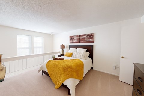 A bedroom with a bed covered in a yellow blanket.