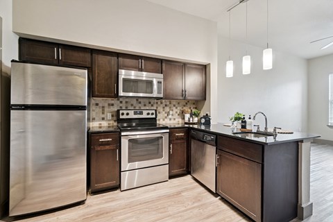 A modern kitchen with dark wood cabinets and stainless steel appliances.