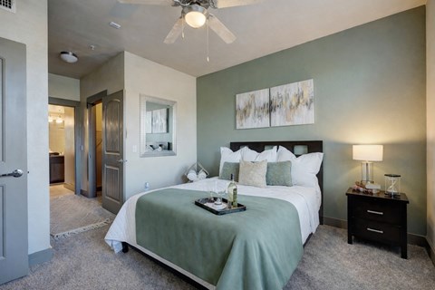 A bedroom with a bed, nightstand, and a ceiling fan.