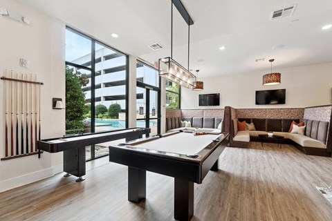 A pool table in a room with a sofa and a TV.