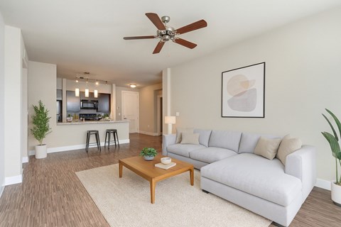 A living room with a white couch, a wooden coffee table, and a ceiling fan.