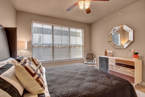 A bedroom with a bed, chair, and a mirror on the wall.