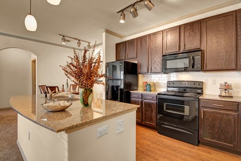 A kitchen with brown cabinets and a black refrigerator.