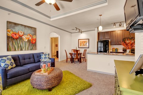 A living room with a blue couch and a painting of tulips on the wall.