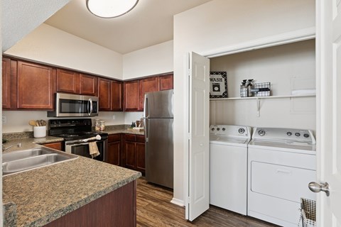 A kitchen with brown cabinets and a white door leading to a laundry room.