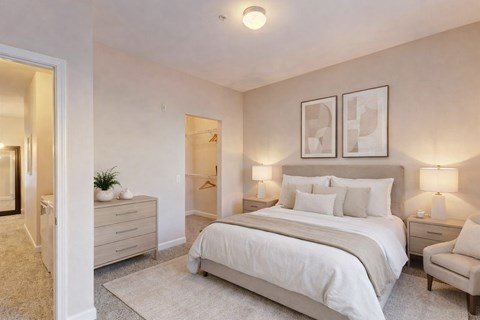 A bedroom with a large bed, two nightstands, and a chair.