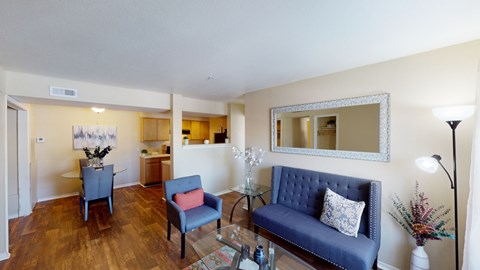 A living room with a blue couch and a mirror on the wall.