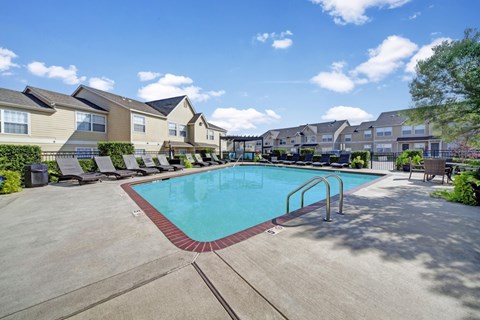 A swimming pool surrounded by a concrete patio and a row of houses.