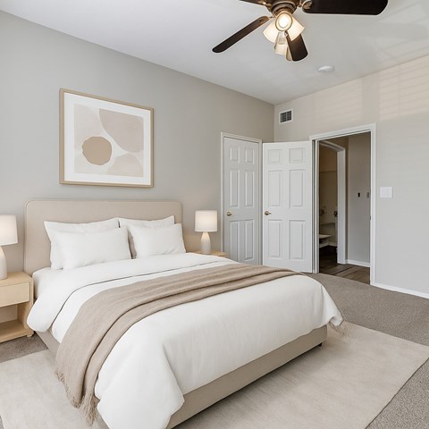 A bedroom with a large bed and a ceiling fan.