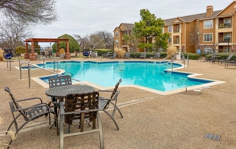 A pool area with chairs and a table.