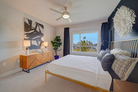 A bedroom with a bed, a dresser, and a ceiling fan.