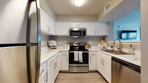 A kitchen with white cabinets and a stainless steel refrigerator.