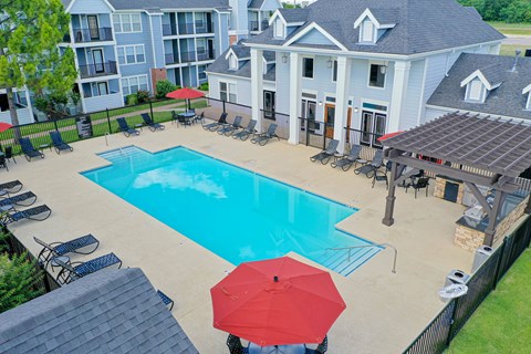 A red umbrella is on a patio next to a pool.
