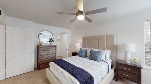 A bedroom with a bed, dresser, and ceiling fan.