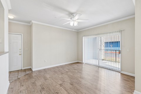 A room with a ceiling fan and sliding glass doors.