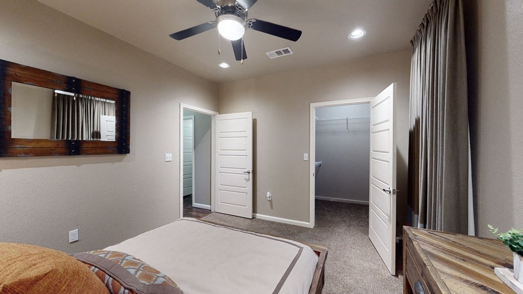 a bedroom with a ceiling fan and a mirror on the wall