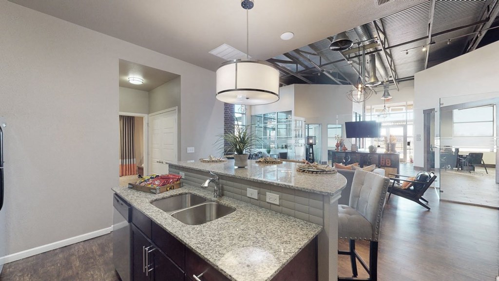 a kitchen with granite countertops and a dining area in the background