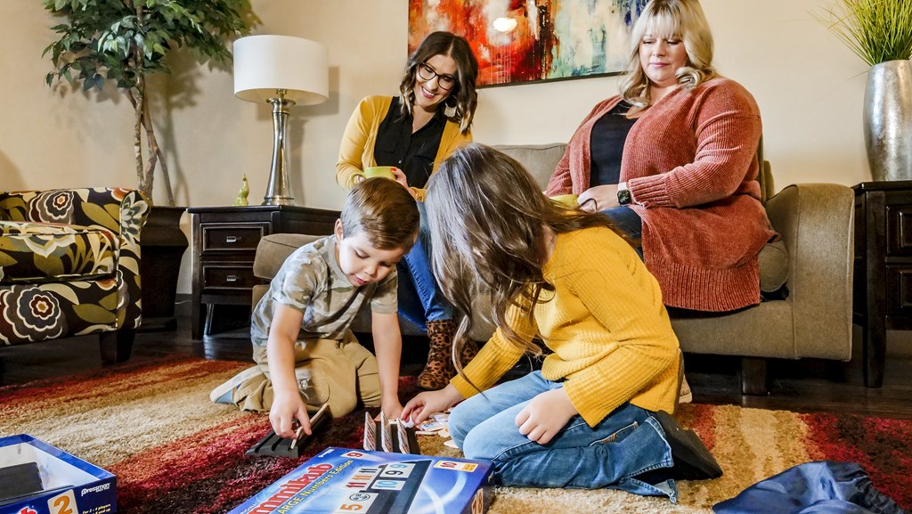 A family playing a board game in a living room at Legends of River Oaks