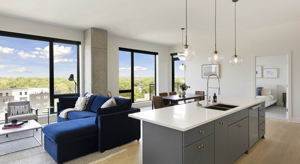 A modern living room with a kitchen area in the background.