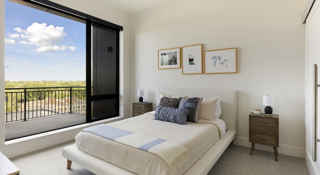 A bedroom with a large bed and a balcony overlooking a field.