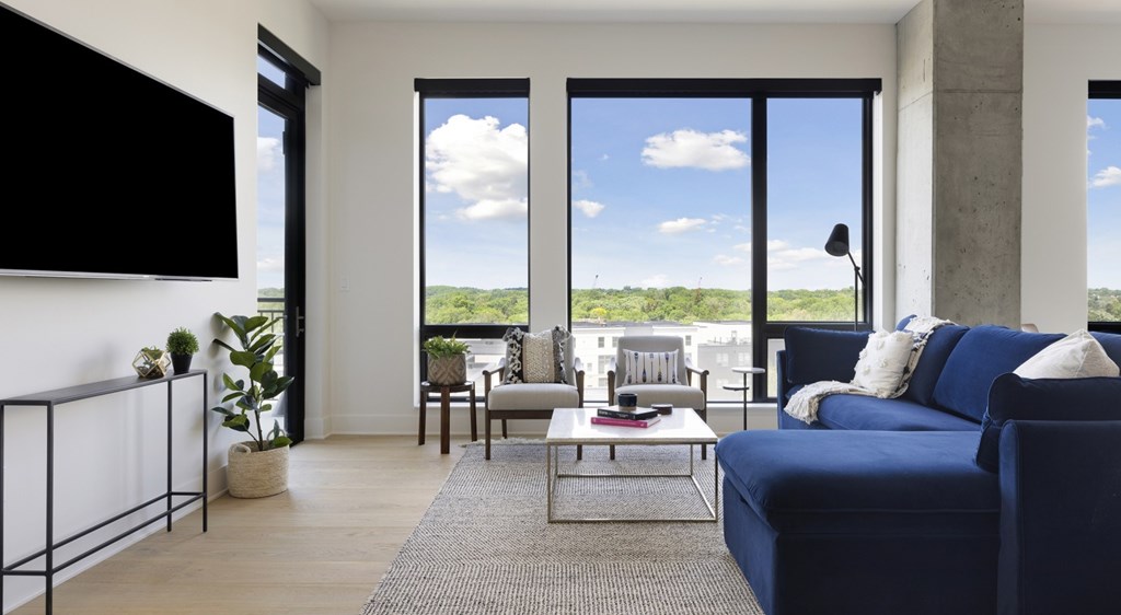 A living room with a blue couch and a flat screen TV mounted on the wall.