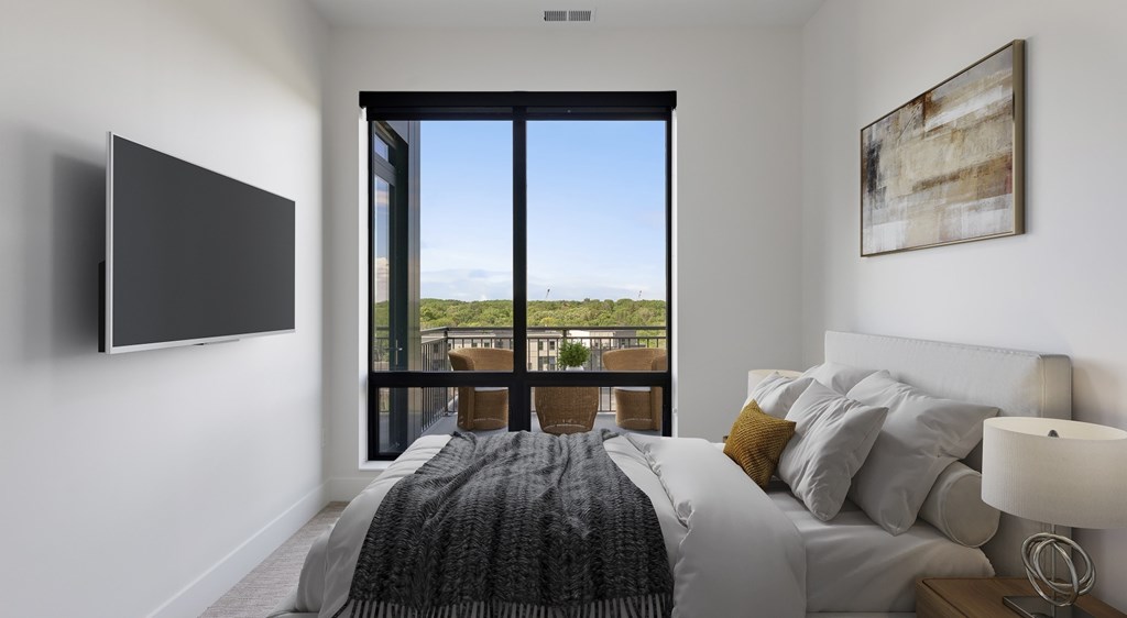A bedroom with a large bed and a flat screen TV mounted on the wall.
