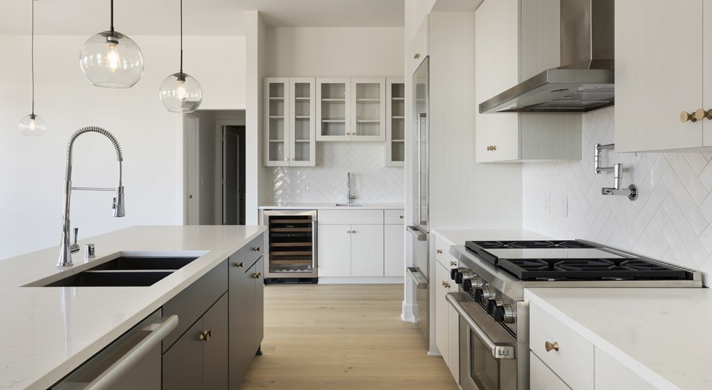 A modern kitchen with a stainless steel sink and white cabinets.