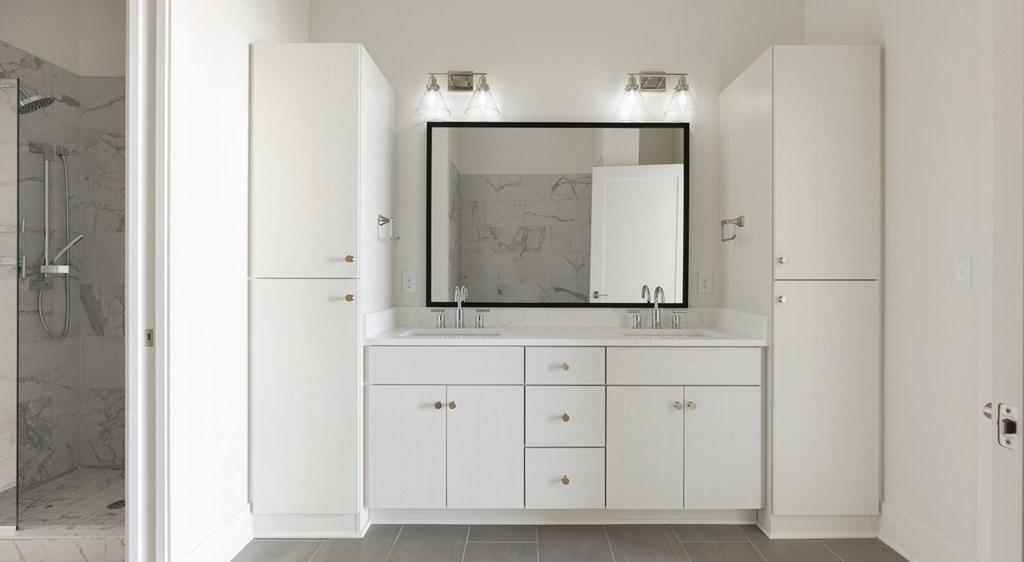 A bathroom with a white cabinet and a mirror above the sink.