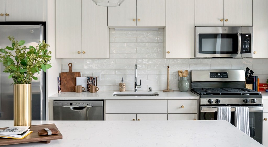 A kitchen with white cabinets and a white countertop.