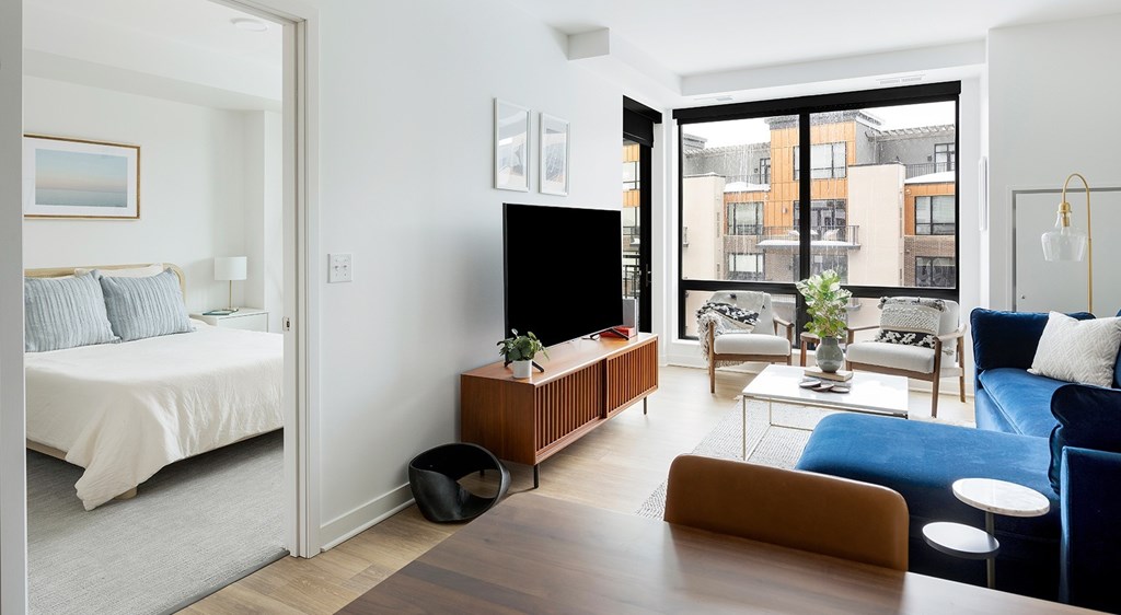 A modern living room with a white bed and a black TV.