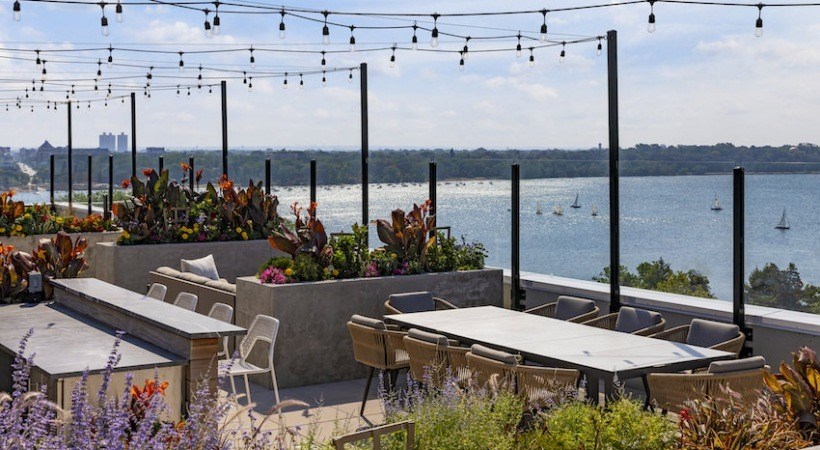 A patio with tables and chairs overlooking a body of water.