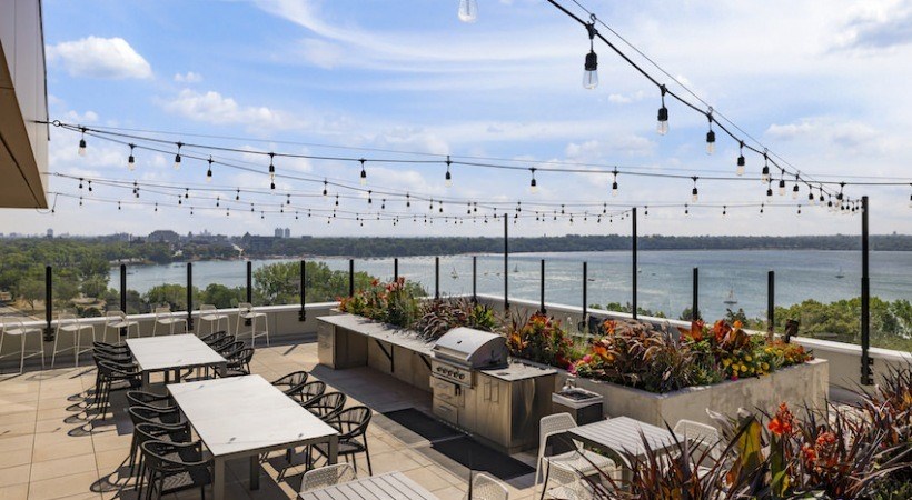 A patio with tables and chairs overlooking a body of water.