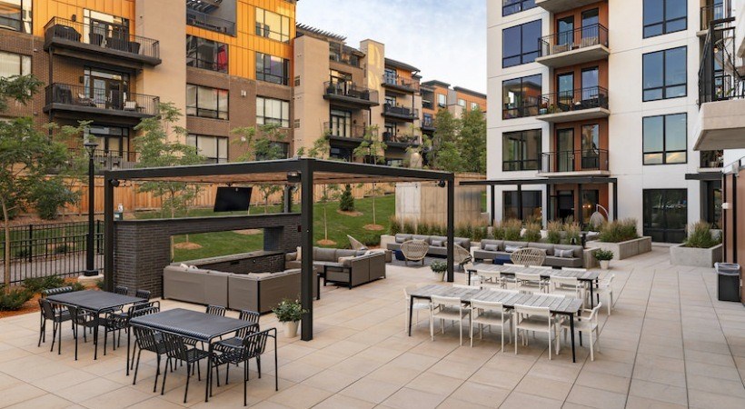 A patio with tables and chairs is surrounded by apartment buildings.