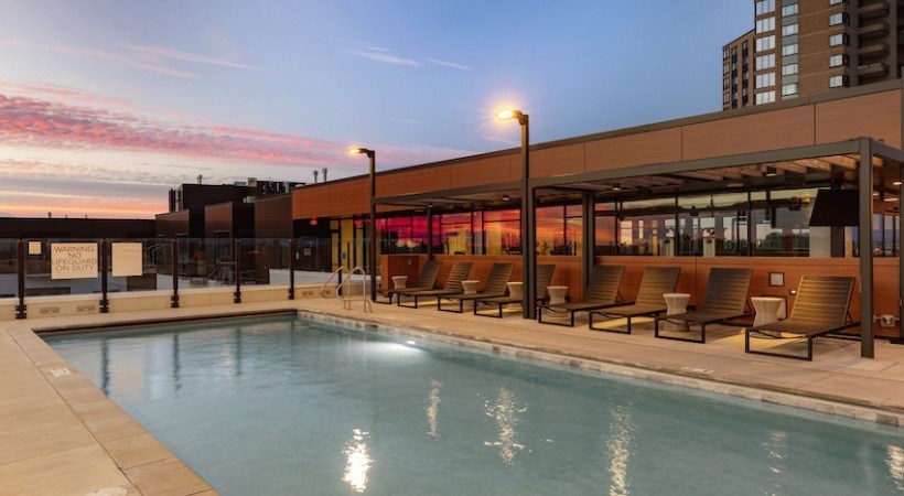 A pool area with lounge chairs and a building in the background.