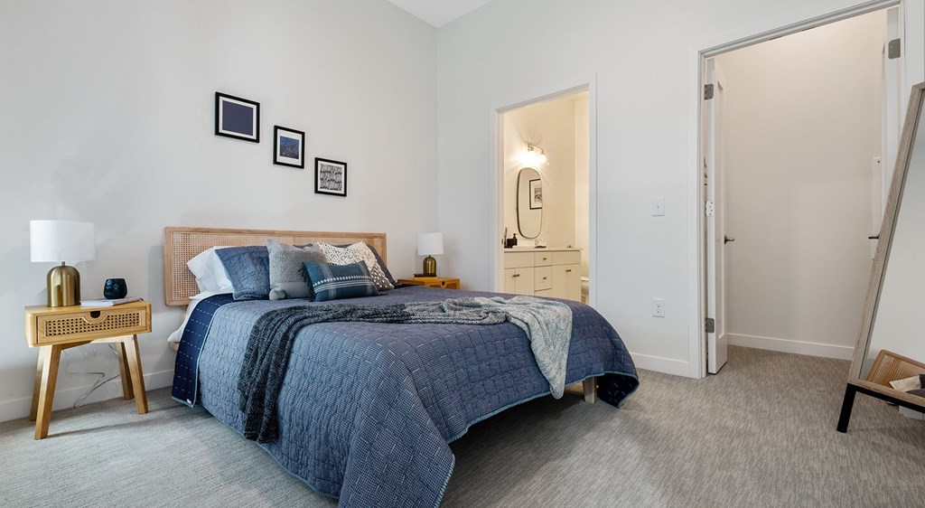 A bedroom with a bed, nightstands, and pictures on the wall.