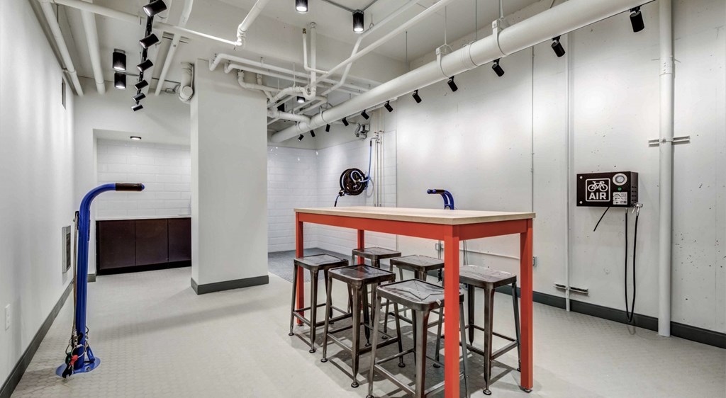 A room with a red table and stools, a broom, and a vacuum cleaner.