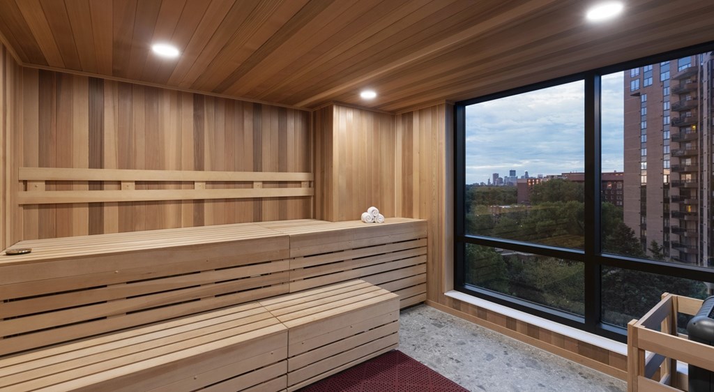 A wooden sauna room with a view of the city outside the window.