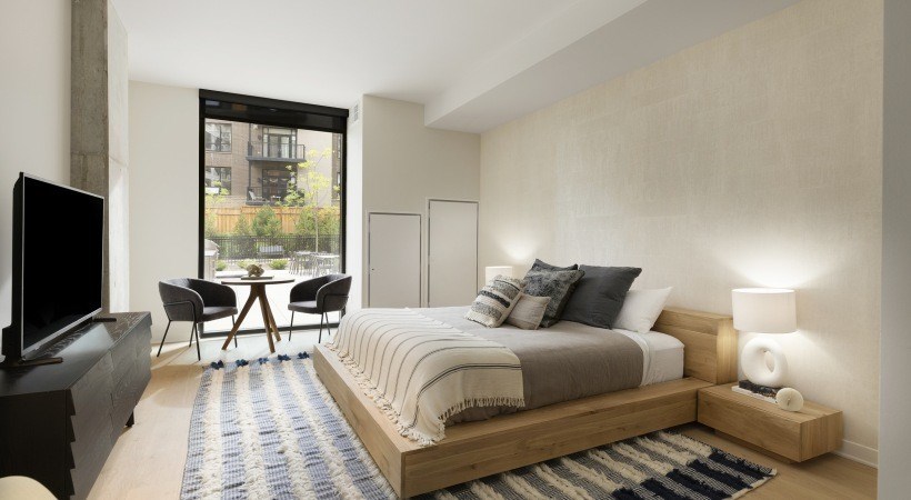 A bedroom with a large bed, a television, and a view of the city.